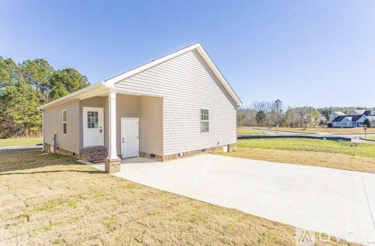 A small white house with a porch and a driveway in front.