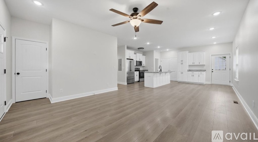 A spacious room with a ceiling fan and wooden flooring.
