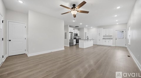 A spacious room with a ceiling fan and wooden flooring.