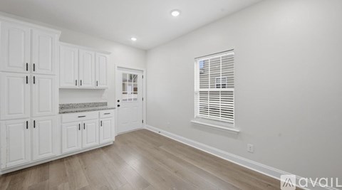 A kitchen with white cabinets and a window with blinds.