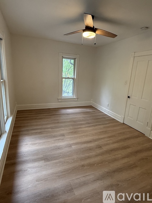 A room with a ceiling fan and wooden flooring.
