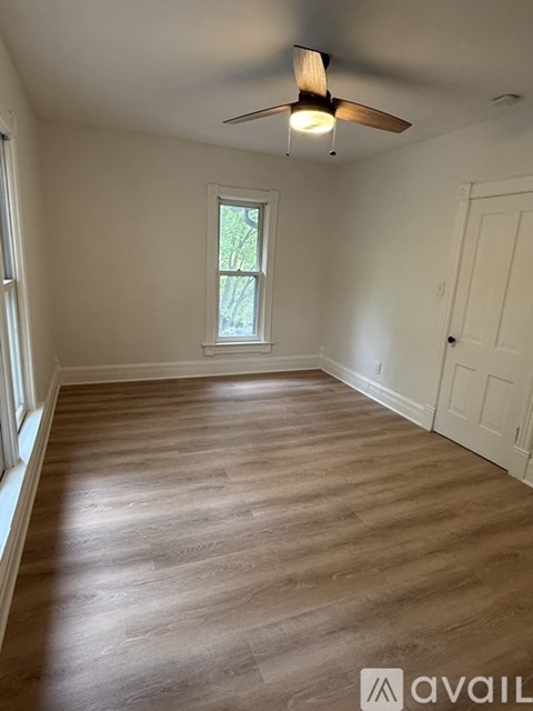 A room with a ceiling fan and wooden flooring.