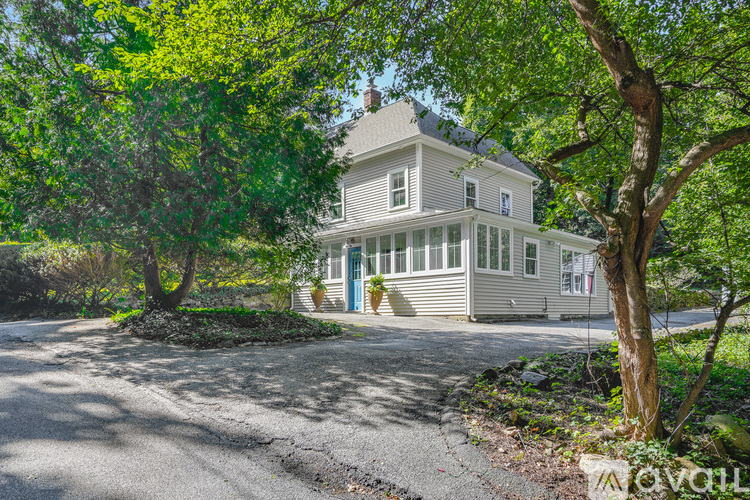 A house with a driveway and trees in front of it.