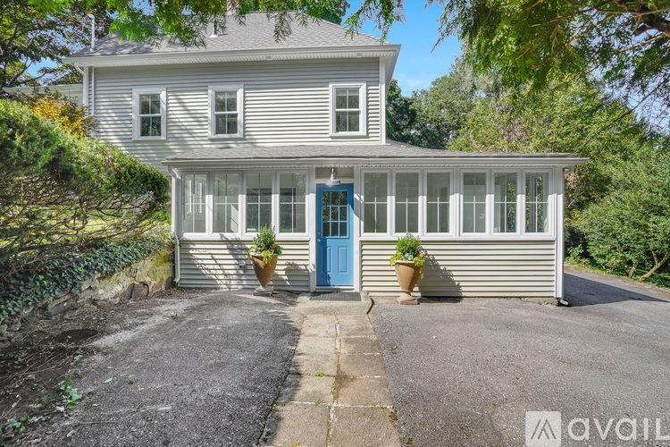 A house with a blue door and windows surrounded by greenery.