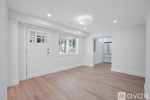 A spacious room with wooden flooring and white walls.