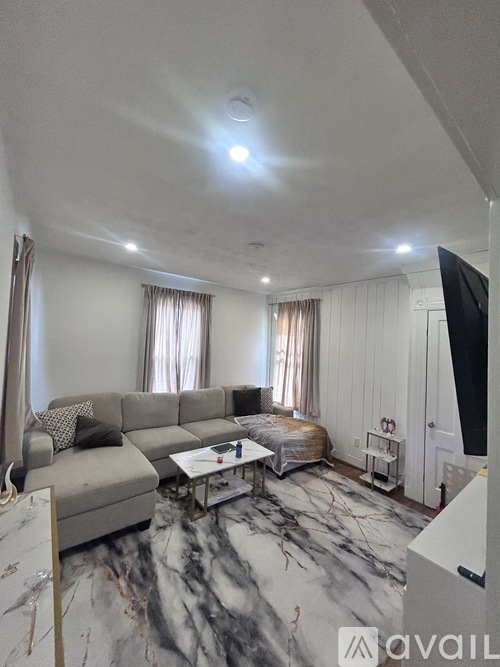 A living room with a grey sofa and a marble floor.