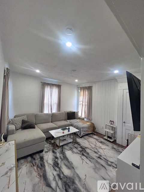A living room with a grey sofa and a marble floor.