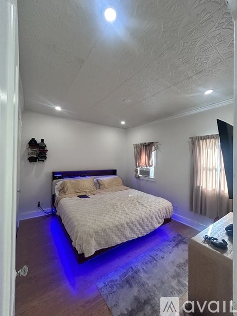 A bedroom with a bed, a television, and a window with curtains.