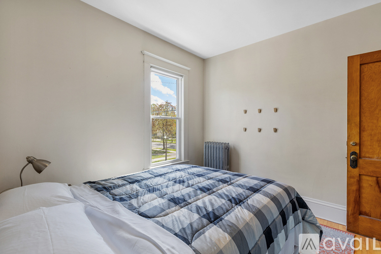 A bedroom with a bed, window, and a door.