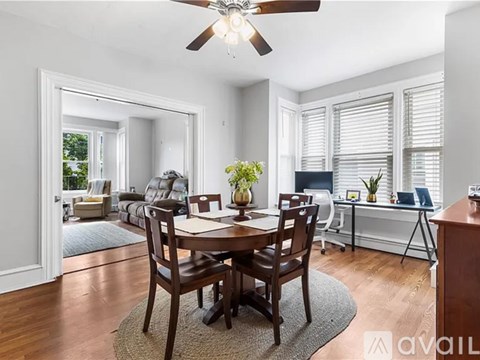 A dining room with a table set for four and a ceiling fan.