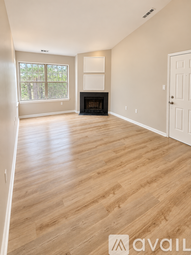 A spacious room with a fireplace and wooden flooring.