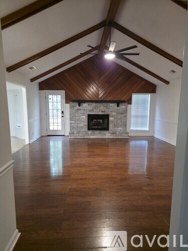 A spacious room with wooden floors and a fireplace.