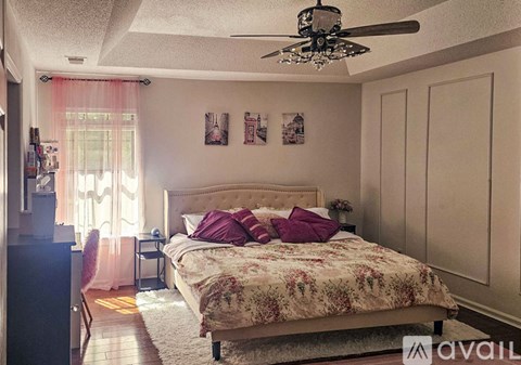 A bedroom with a large bed and a ceiling fan.
