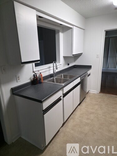 A kitchen with white cabinets and a black countertop.