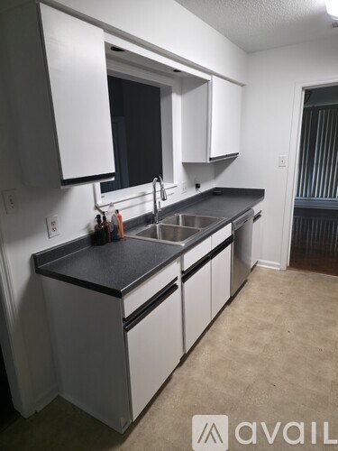 A kitchen with white cabinets and a black countertop.