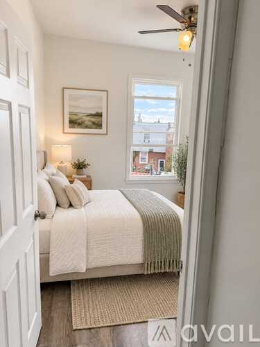 A bedroom with a bed, a window, and a ceiling fan.