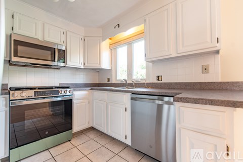 A kitchen with white cabinets and a stainless steel dishwasher.