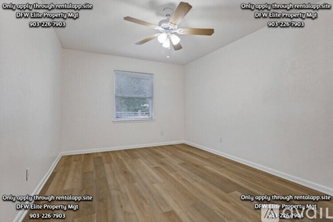 A room with a ceiling fan and a window with a view of trees.