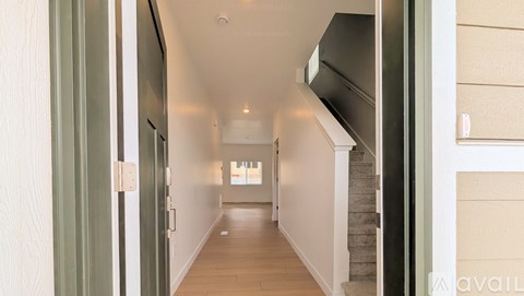 A long hallway with a staircase on the right and a window in the distance.