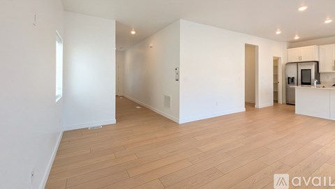 A spacious room with wooden flooring and white walls.