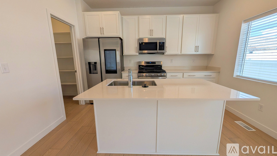A kitchen with white cabinets and a white island with a sink.