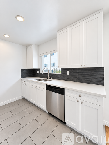 A kitchen with white cabinets and a black countertop.