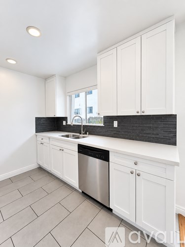 A kitchen with white cabinets and a black countertop.