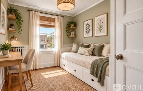 A cozy bedroom with a window seat and a bed with a green throw.