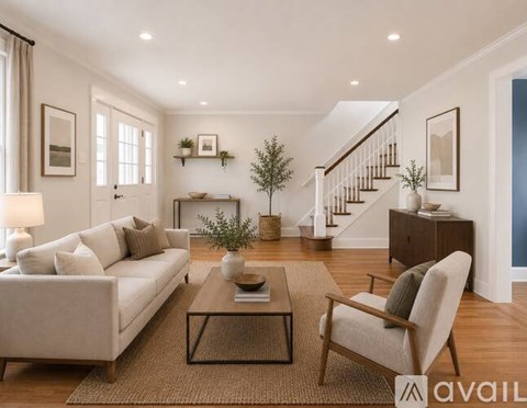 A living room with a white couch, a coffee table, and a chair.