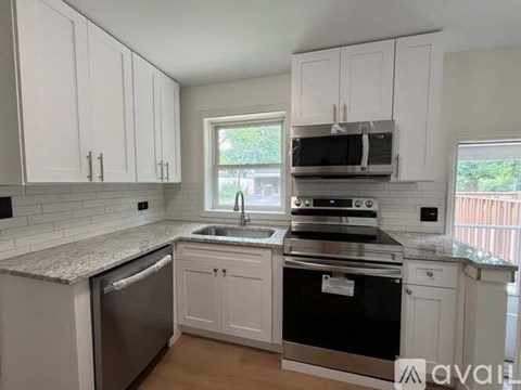 A kitchen with white cabinets and a granite countertop.