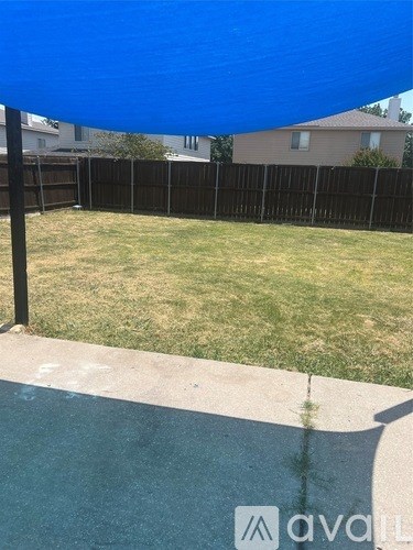 A backyard with a blue shade sail over a pool.