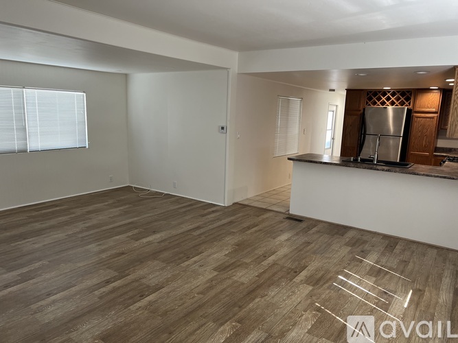 A spacious living room with a kitchenette in the background.