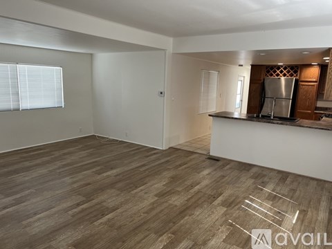 A spacious living room with a kitchenette in the background.