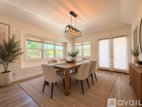 A dining room with a table set for four and a chandelier hanging from the ceiling.