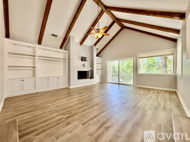 A spacious attic room with wooden floors and white walls.