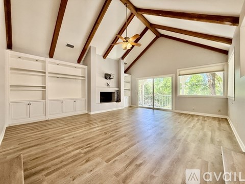 A spacious attic room with wooden floors and white walls.
