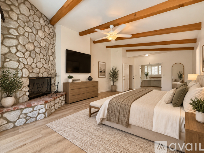A bedroom with a stone fireplace and a large bed.