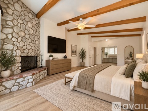 A bedroom with a stone fireplace and a large bed.