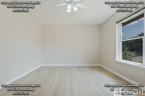 A room with a fan and a window showing trees outside.