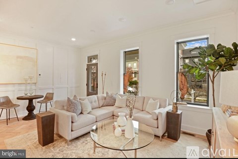 A living room with a white couch and a glass coffee table.