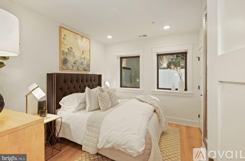 A bedroom with a large bed and a painting on the wall.