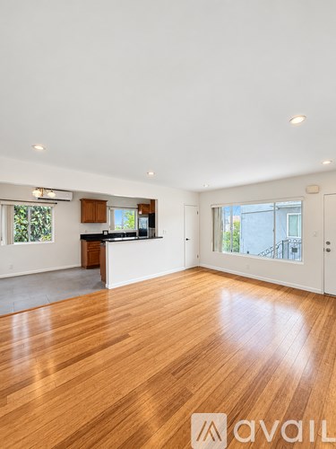A spacious room with wooden floors and a kitchen area.