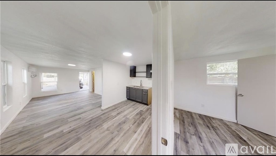 A spacious room with wooden flooring and white walls.