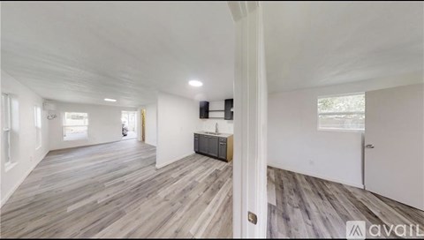 A spacious room with wooden flooring and white walls.