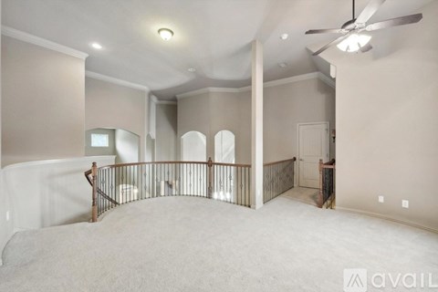 A spacious room with a fan and a staircase.