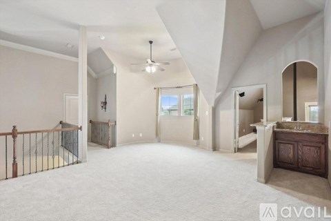 A spacious living room with a balcony and a ceiling fan.