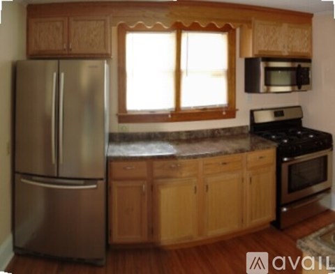 A kitchen with wooden cabinets and a stainless steel refrigerator.