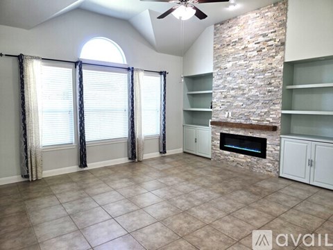 A living room with a stone fireplace and a ceiling fan.