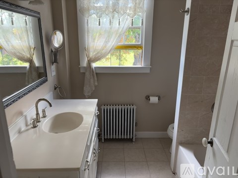 A bathroom with a white sink and a window with curtains.