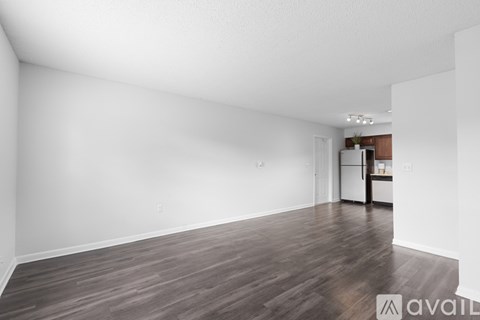 A spacious room with wooden flooring and white walls.